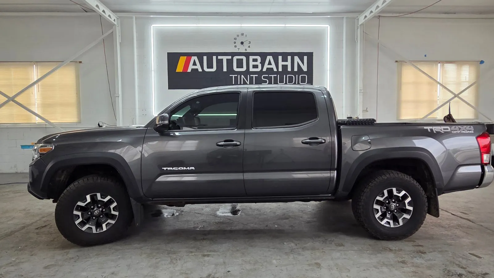 Gray Toyota Tacoma with fresh tint parked in front of the Autobahn Tint Studio sign inside the shop